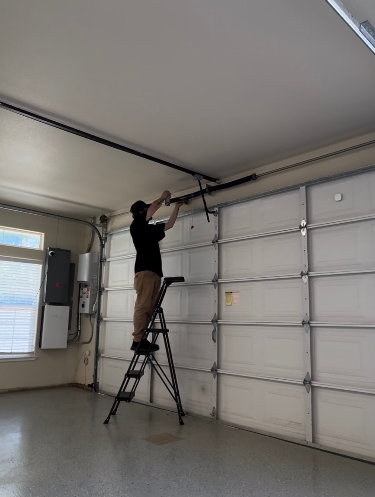 Servicing an opener rail from a step ladder inside a garage