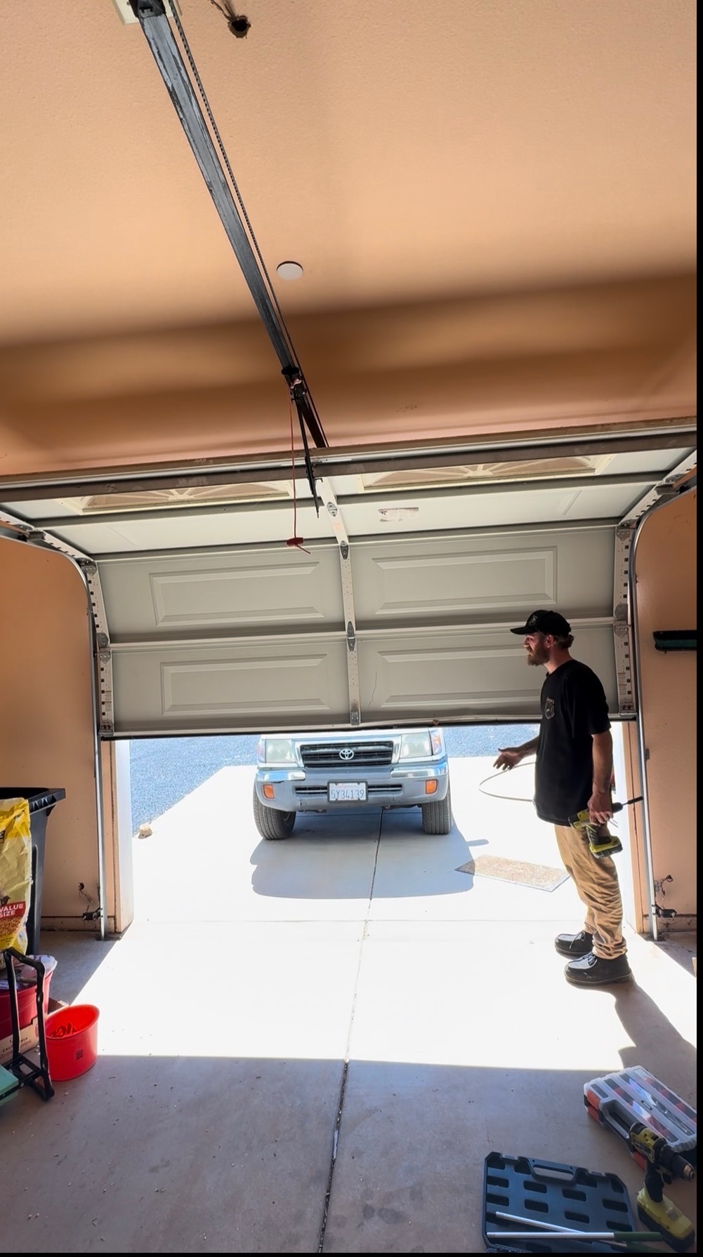 Sloan pulling a new opener wire at an open sectional garage door